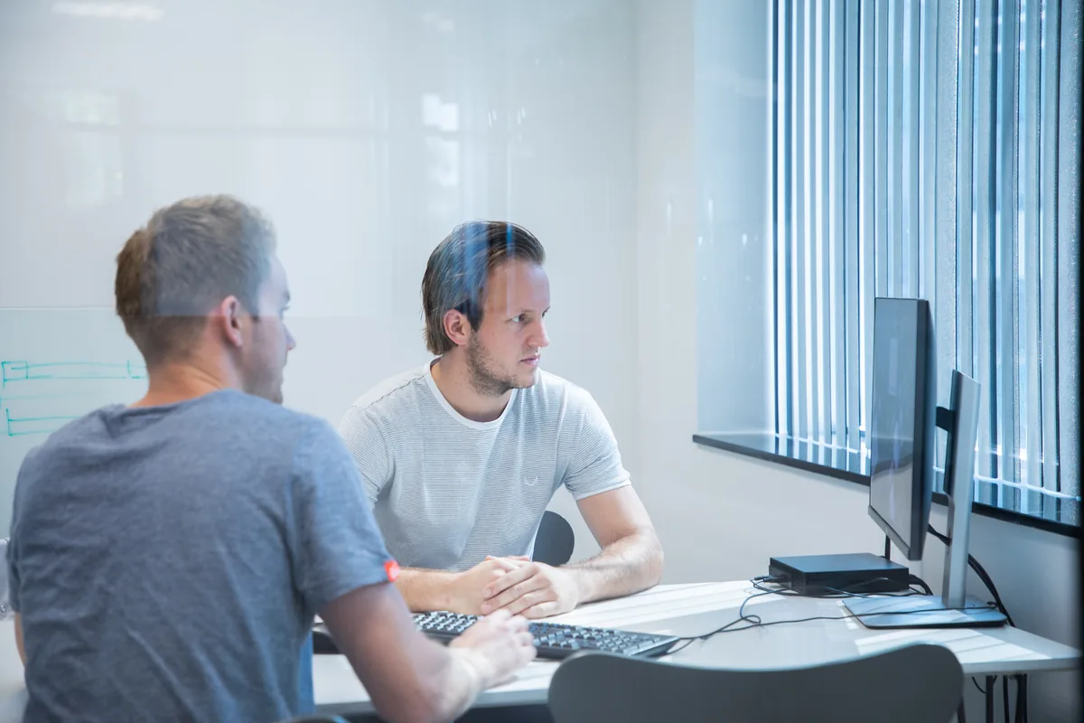 Twee Prodrive Technologies engineers werken samen achter computer tijdens code review