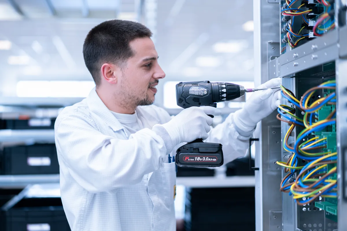 Prodrive Technologies technician bekabelt elektronicapaneel met boormachine in assemblagehall